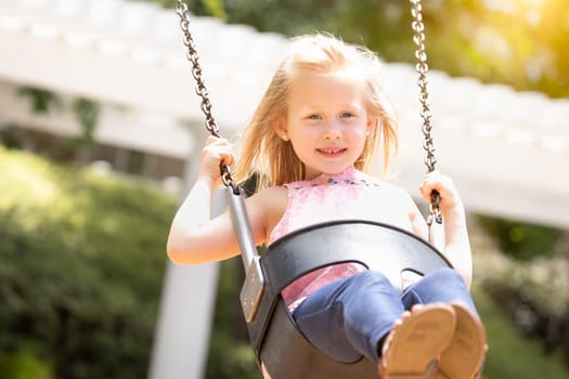 Pretty Young Girl Having Fun On The Swings At The Playground.
