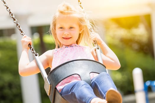 Pretty Young Girl Having Fun On The Swings At The Playground.