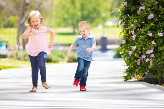 Young Sister and Brother Having Fun Running At The Park.