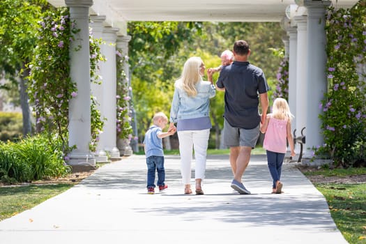 Young Caucasian Family Taking A Walk In The Park.