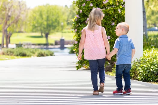 Young Sister and Brother Holding Hands And Walking At The Park.