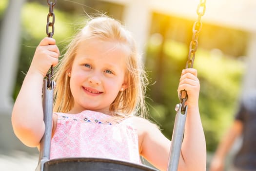Pretty Young Girl Having Fun On The Swings At The Playground.