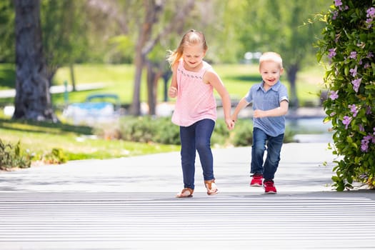 Young Sister and Brother Having Fun Running At The Park.