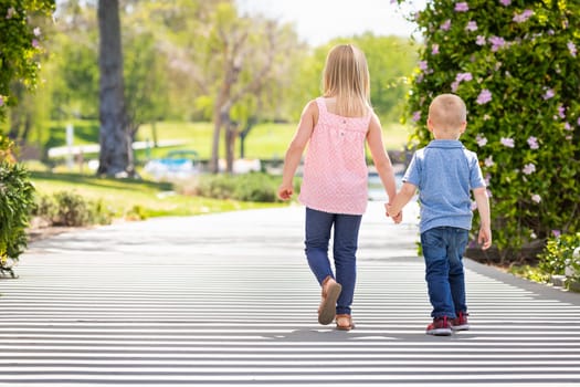 Young Sister and Brother Holding Hands And Walking At The Park.