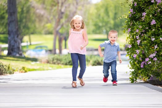 Young Sister and Brother Having Fun Running At The Park.