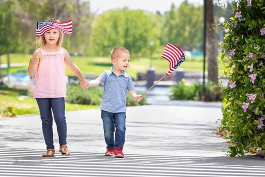 Young Sister and Brother Waving American Flags At The Park.