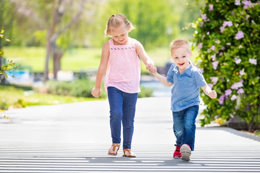 Young Sister and Brother Holding Hands And Walking At The Park.
