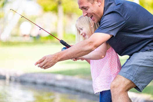 Young Caucasian Father and Daughter Having Fun Fishing At The Lake.