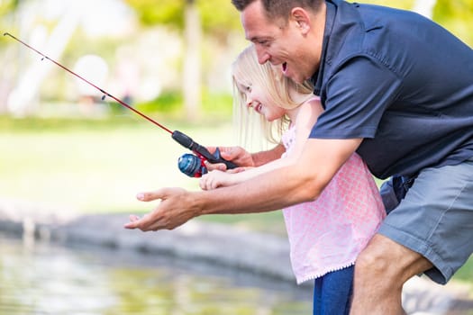 Young Caucasian Father and Daughter Having Fun Fishing At The Lake.