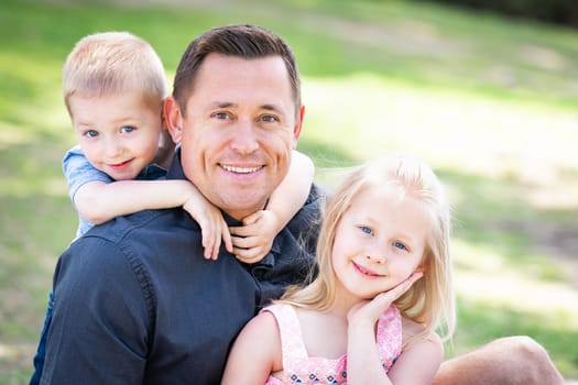 Young Caucasian Dad, Son and Daughter Having Fun In The Park.