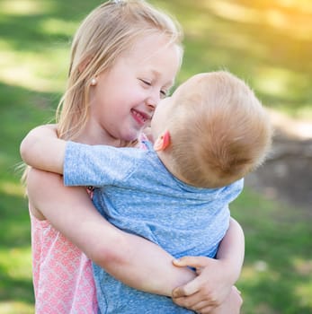 Young Brother and Sister Hugging At The Park.