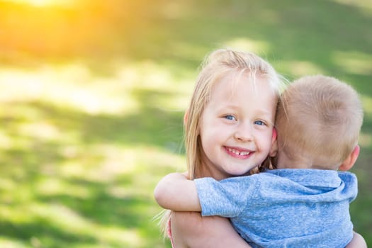 Young Brother and Sister Hugging At The Park.