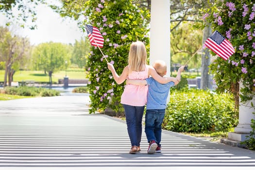 Young Sister and Brother Waving American Flags At The Park.