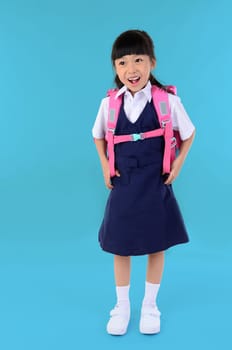 Back to school. Portrait of happy asian cute little child girl in uniform with school bag smiling when go back to school, isolated blue background.
