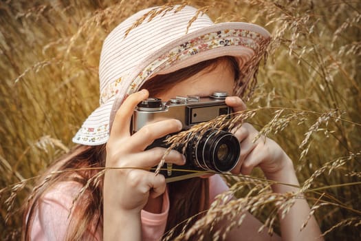 Girl taking photo outdoors with old camera. Selective focus at lens, unrecognizable person. Lifestyle portrait, soft toned