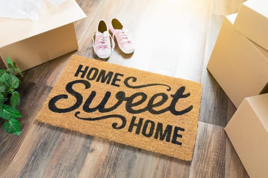 Home Sweet Home Welcome Mat, Moving Boxes, Pink Shoes and Plant on Hard Wood Floors.