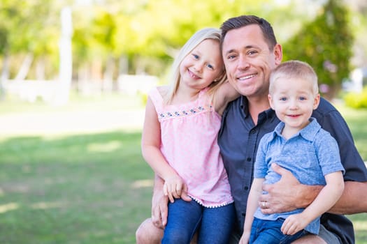 Young Caucasian Dad, Son and Daughter Having Fun In The Park.