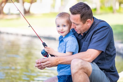 Young Caucasian Father and Son Having Fun Fishing At The Lake.