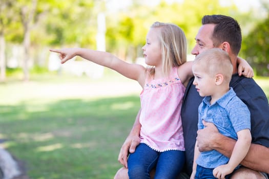 Young Caucasian Dad, Son and Daughter Having Fun In The Park.