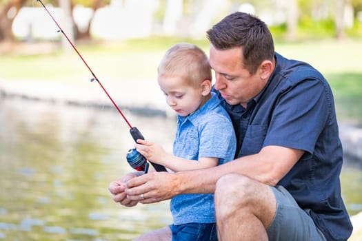 Young Caucasian Father and Son Having Fun Fishing At The Lake.