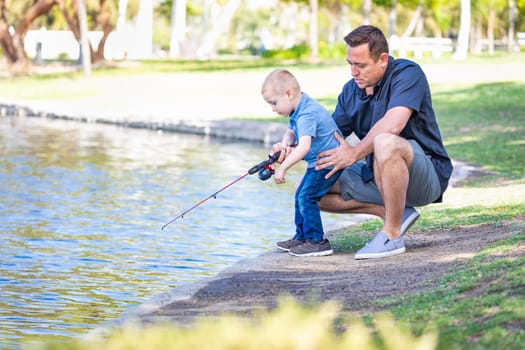 Young Caucasian Father and Son Having Fun Fishing At The Lake.