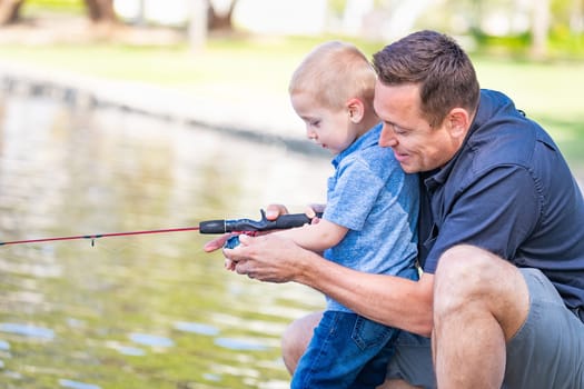 Young Caucasian Father and Son Having Fun Fishing At The Lake.