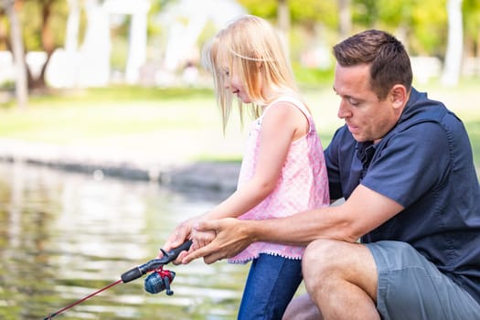 Young Caucasian Father and Daughter Having Fun Fishing At The Lake.