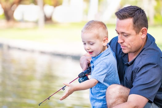 Young Caucasian Father and Son Having Fun Fishing At The Lake.