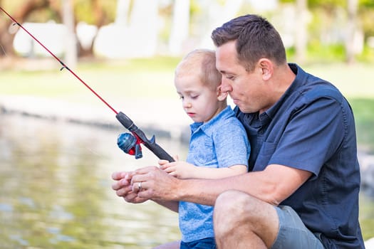 Young Caucasian Father and Son Having Fun Fishing At The Lake.