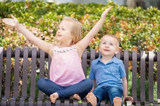 Young Sister and Brother Having Fun On The Bench At The Park.