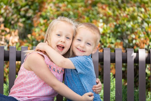 Young Sister and Brother Having Fun On The Bench At The Park.