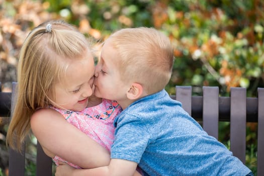 Young Sister and Brother Having Fun On The Bench At The Park.