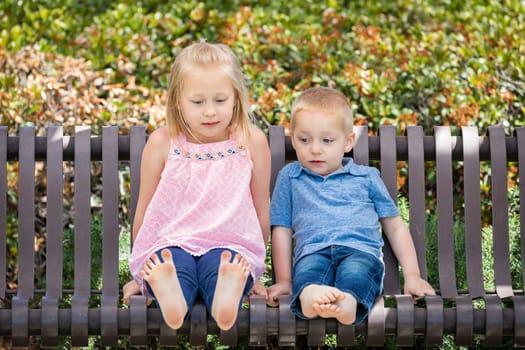 Young Sister and Brother Having Fun On The Bench At The Park.