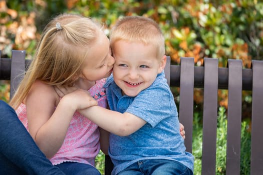 Young Sister and Brother Having Fun On The Bench At The Park.