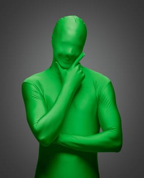 Thinking Man with Hand on Chin Wearing Full Green Nylon Bodysuit on a Grey Background..