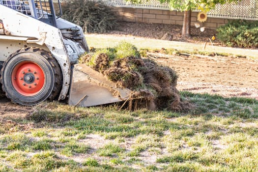 Small Bulldozer Removing Grass From Yard Preparing For Pool Installation.