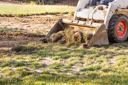 Small Bulldozer Removing Grass From Yard Preparing For Pool Installation.