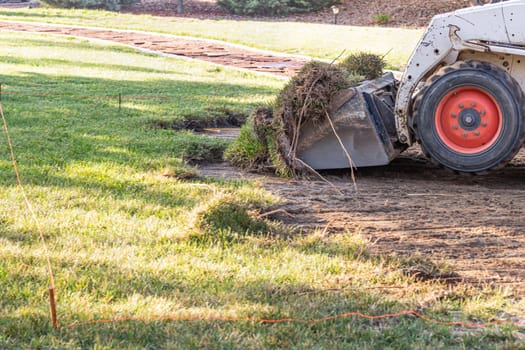 Small Bulldozer Removing Grass From Yard Preparing For Pool Installation.