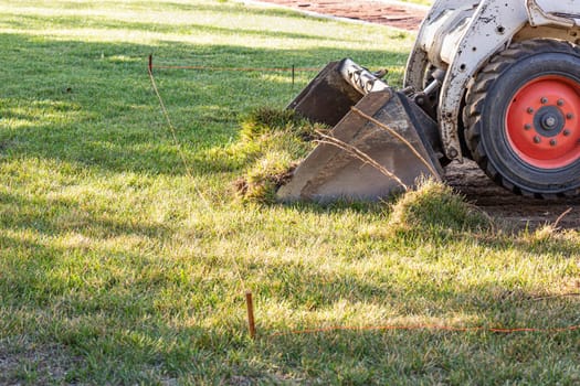Small Bulldozer Removing Grass From Yard Preparing For Pool Installation.
