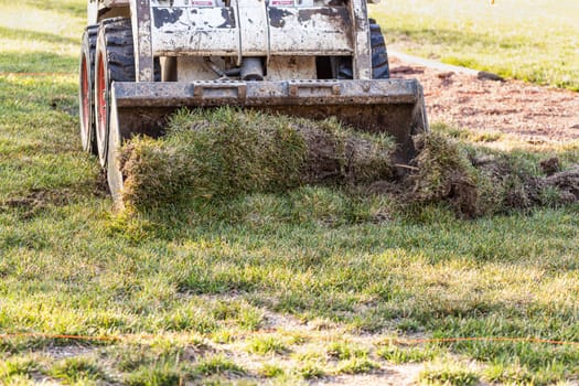 Small Bulldozer Removing Grass From Yard Preparing For Pool Installation.