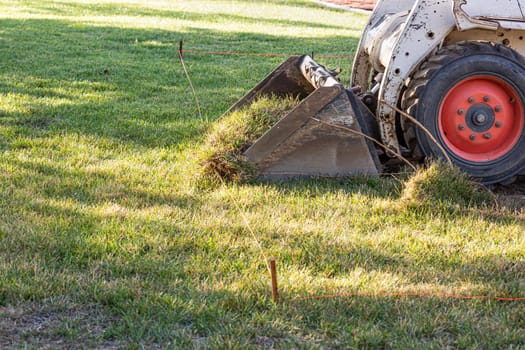 Small Bulldozer Removing Grass From Yard Preparing For Pool Installation.