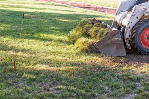 Small Bulldozer Removing Grass From Yard Preparing For Pool Installation.
