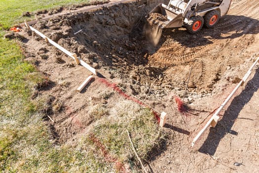 Small Bulldozer Digging In Yard For Pool Installation.