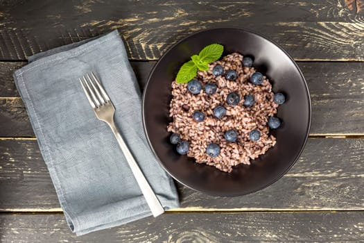 Fresh and healthy vegan rice bowl served with bilberry fruits. Diet concept. Copy space for recipes. Image for your food blog on socials. Flatlay.
