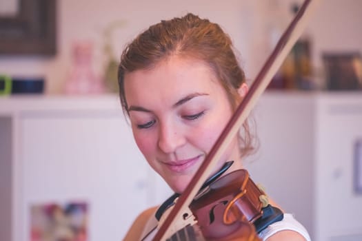 Pretty young girl practices on her violin, acoustic music