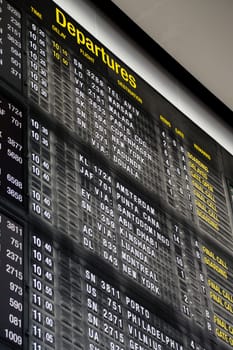 Airport departure board in terminal with flight information