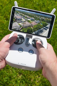 Hands Holding Drone Quadcopter Controller With Residential Homes on Screen.