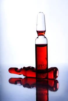 Closeup of two medical ampoules with red liquid inside
