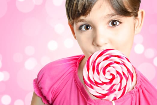 Beautiful little girl with lollipop in front of the pink background
