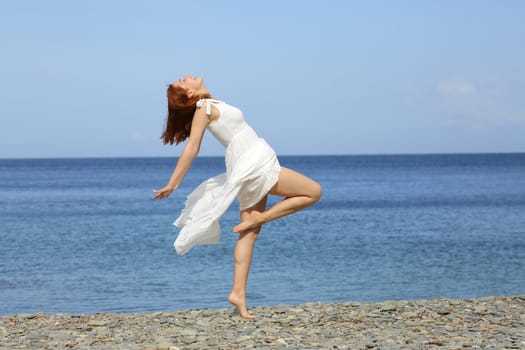 Woman in white dress posing showing legs on the beach